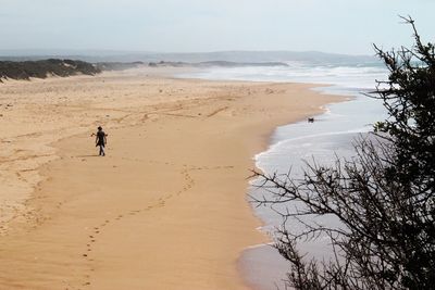 Person walking at beach against sky