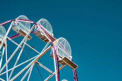 Low angle view of ferris wheel against clear blue sky