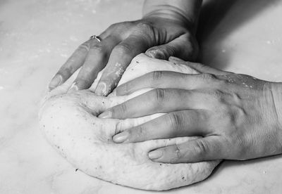 Cropped hands of person making dough on marble
