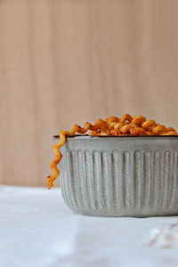 A long fusillone pasta protrudes from the ceramic bowl. vertical.