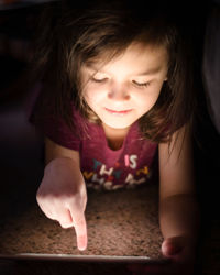 Girl using digital table while lying on floor at home