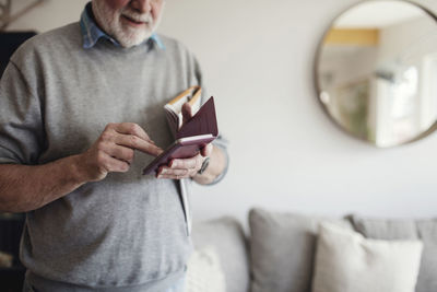 Midsection of senior man using mobile phone while standing in living room