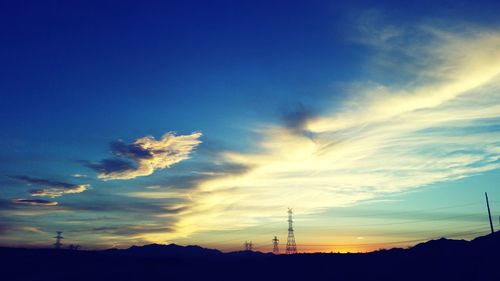 Silhouette of electricity pylon at sunset