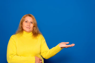 Portrait of young woman against blue background