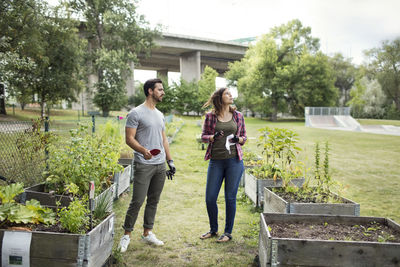 Full length of mid adult couple standing amidst plants in urban garden