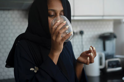 Muslim woman wearing abaya breaking fast during ramadan eating dates drinking water