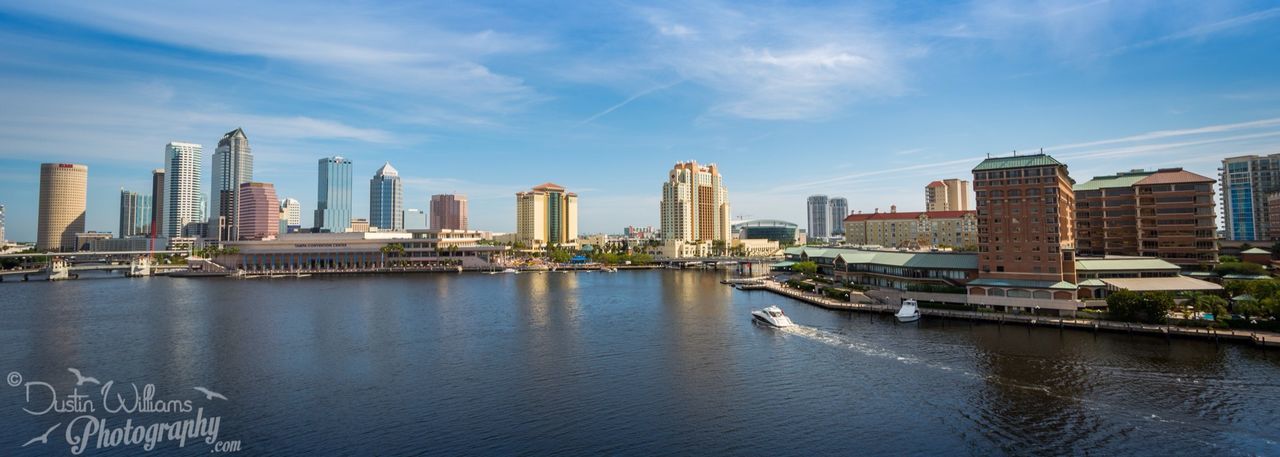 building exterior, architecture, city, built structure, water, sky, skyscraper, waterfront, cityscape, river, urban skyline, tall - high, office building, modern, cloud - sky, blue, cloud, reflection, tower, nautical vessel