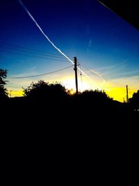 Low angle view of silhouette electricity pylon against sky during sunset