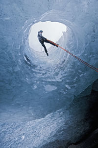 Man rappelling into glacier cave on sólheimajökull glacier in iceland