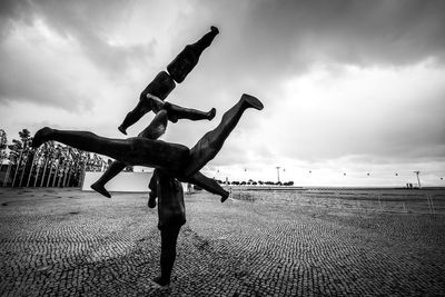 Low angle view of men skateboarding on shore against sky