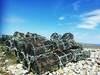 Stack of fishing net on beach against blue sky