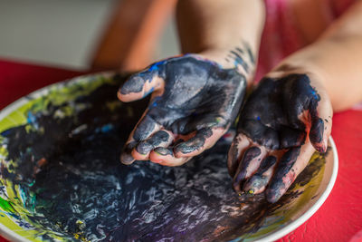High angle view of painted girl hands over plate on table