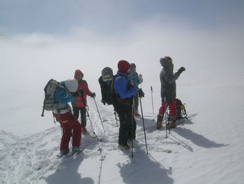 People standing on snowcapped mountain against clear sky