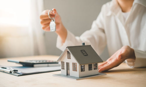 Midsection of businessman holding model house