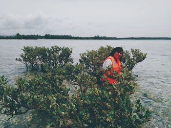 Man and plants by sea against sky
