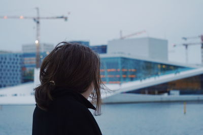 Rear view of woman in city against sky