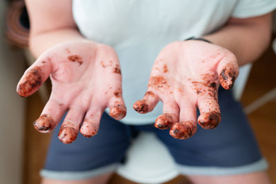 The man shows his hands, all fingers covered in melted chocolate. fun, birthday, celebration