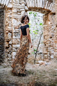 Portrait of young woman standing against wall