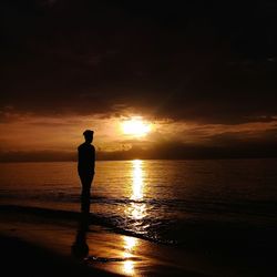 Silhouette man standing at beach during sunset