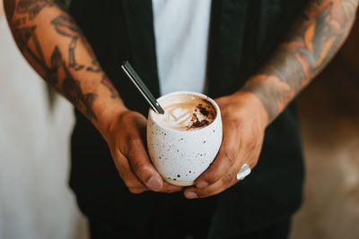 Midsection of man holding coffee cup