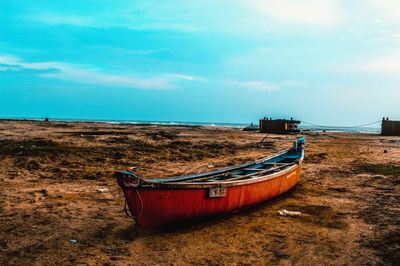 Boat moored on beach against sky