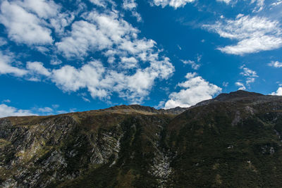 Low angle view of mountain range against cloudy sky