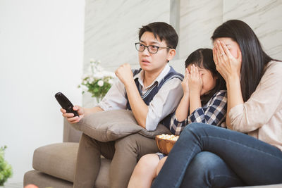 Young woman using phone while sitting on sofa