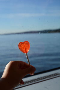 Close-up of hand holding lollipop against sky