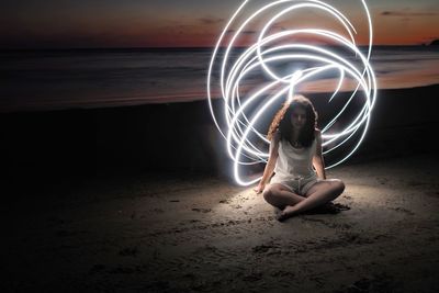 Digital composite image of woman sitting on beach