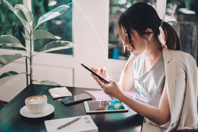 Young woman using mobile phone on table