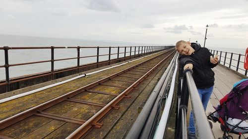 People at observation point by sea against sky