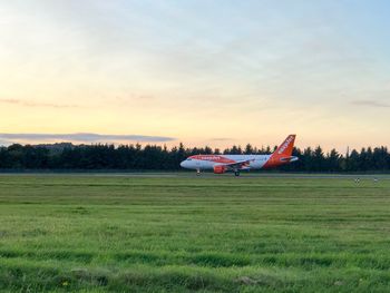 Airplane flying over grassy field against sky
