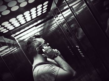 Tilt image of man using smart phone in elevator