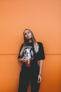 Portrait of young woman standing against wall