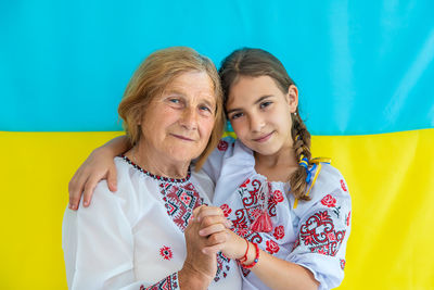 Smiling girl with grandmother standing against ukrainian flag