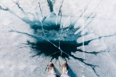 Low section of person standing on frozen lake during winter