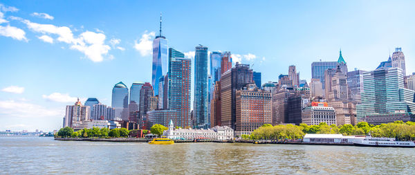 Modern buildings by river against sky in city