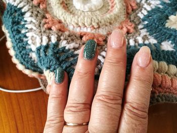 Cropped hand of woman with painted nails on table