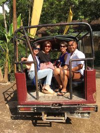 Portrait of happy friends sitting in off-road vehicle