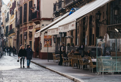 Rear view of people walking on street in city