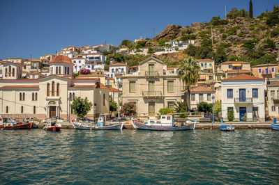 Sailboats moored in canal by buildings in city against sky