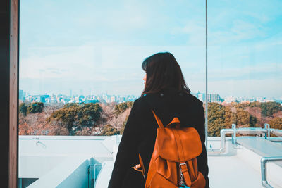 Rear view of woman with backpack standing against sky