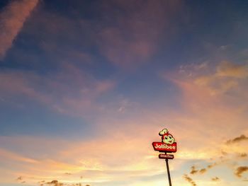 Low angle view of road sign against sky during sunset