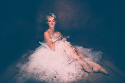 Semi-naked woman wearing tulle tutu against black background