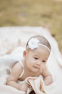 Cute baby girl wearing costume wing while lying on blanket