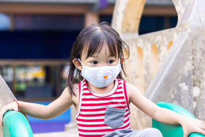 Close-up of cute girl wearing mask sitting on slide