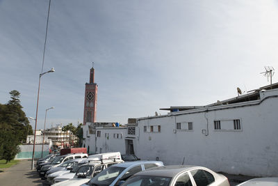 Cars on street by buildings against sky