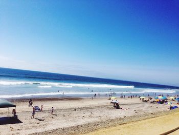 People at beach against blue sky