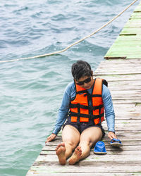 Boy sitting on pier over lake