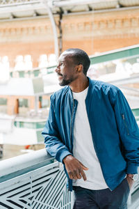 Afro american young stylish man standing in station with mobile phone